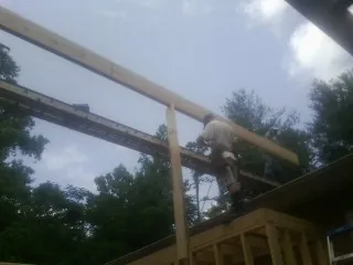 Carpenter setting a ridge beam over a new addition frame — Ice Dam Removal by Roofing Brothers in Balsam