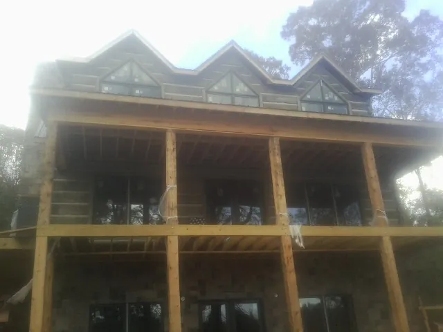 Dormers and porch framing on a large log home under construction — Roof Coating work by our crew in Balsam
