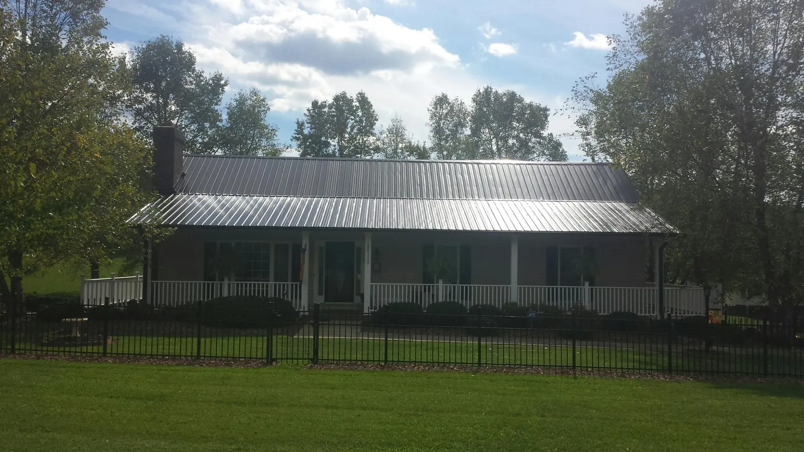 Gray metal roof on a brick ranch with a full width front porch — Gutter Guard Installation work by our crew in Balsam