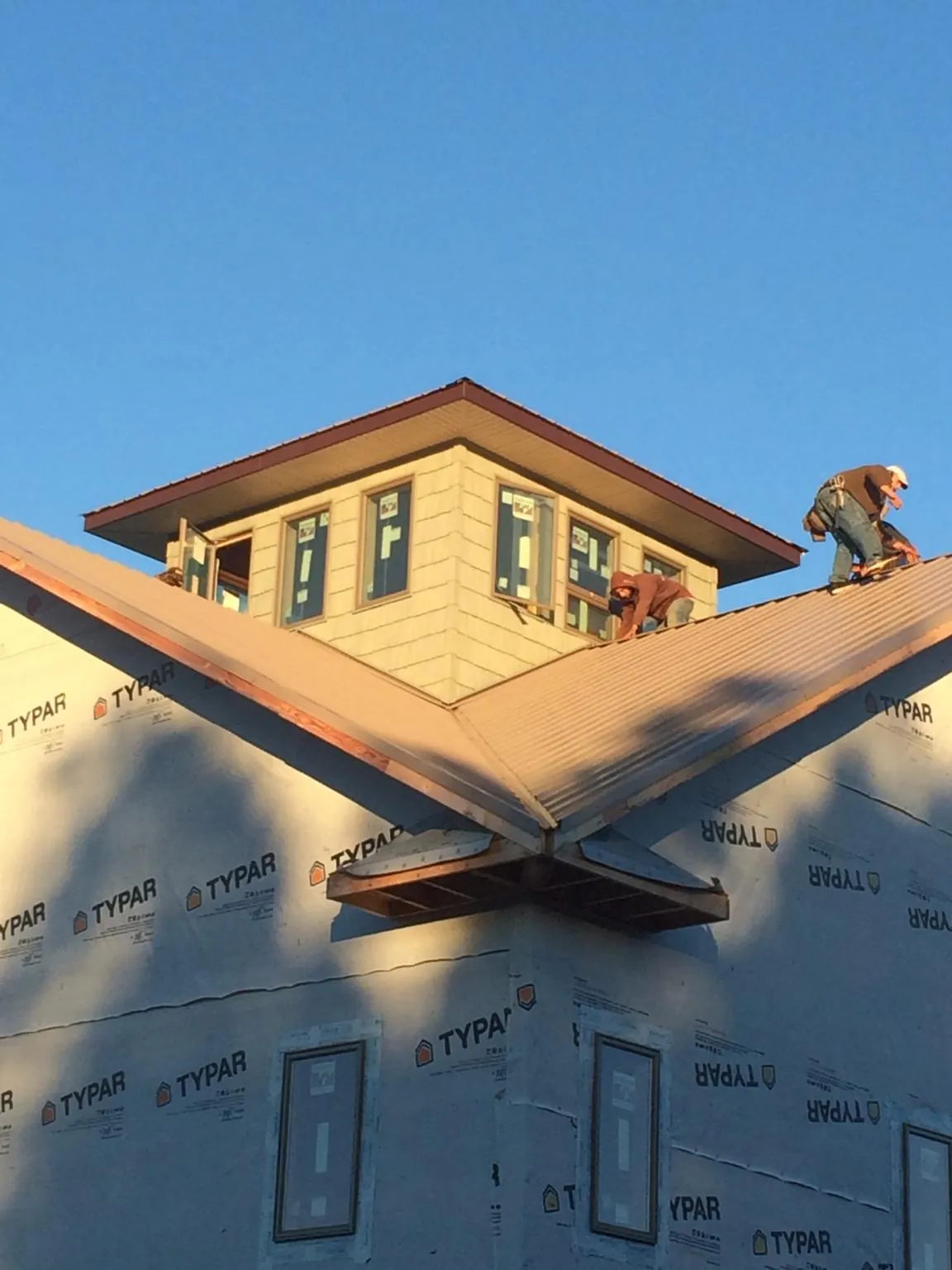 Roofers working around a rooftop cupola on a new metal roof at sunset — Roof Waterproofing in Balsam by Roofing Brothers